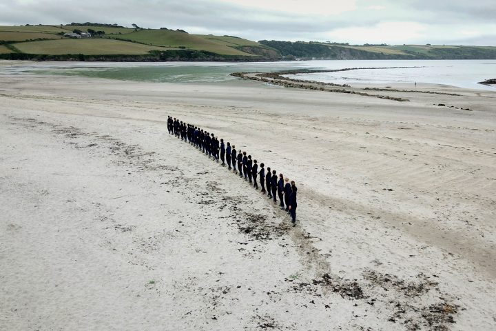 Choreographed line of performers on an empty beach