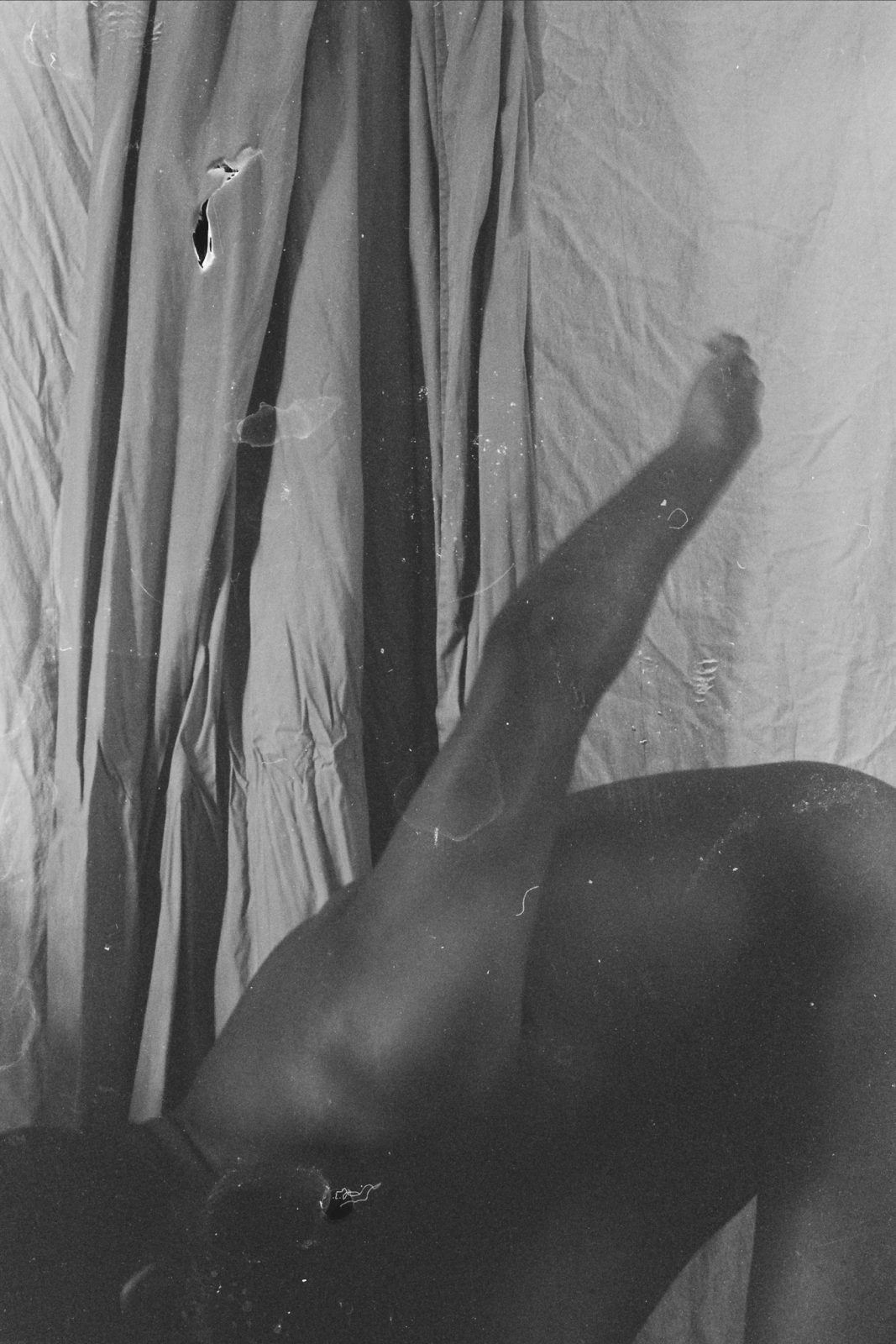 black and white image of a person bent forward, naked, with one arm up