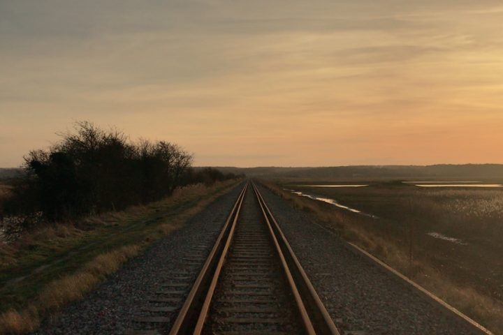 train track in a flat rural location with a pink sky