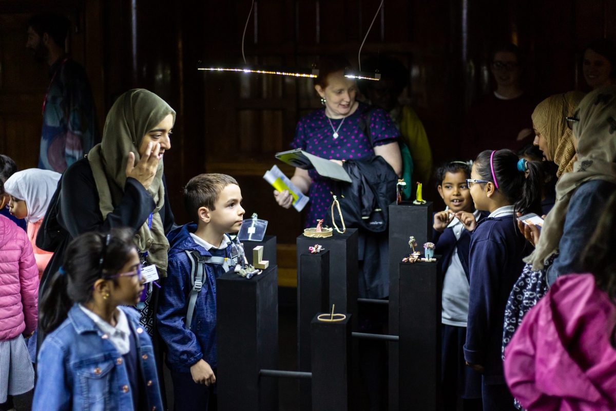 adults and children looking at miniature objects in a gallery