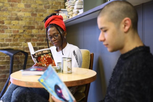 Two people sit at a table reading books