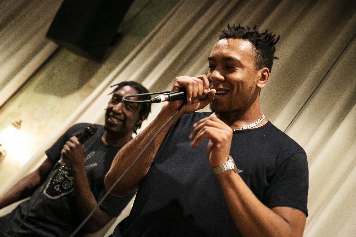 two performer speaking into a mic and smiling