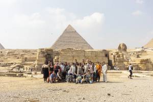 A group shot of the Another Route fellows, partners and producers standing in front of the Great Pyramid of Giza on a hot, sunny day