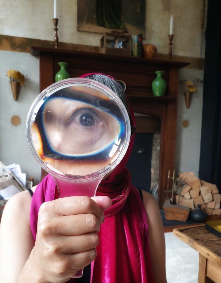 Stacy holds a magnifying glass up to her eye