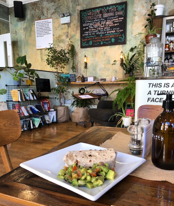 Plate of food with a wrap and salad on a table in a cafe