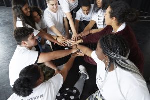a circle of young people with their hands together in the middle