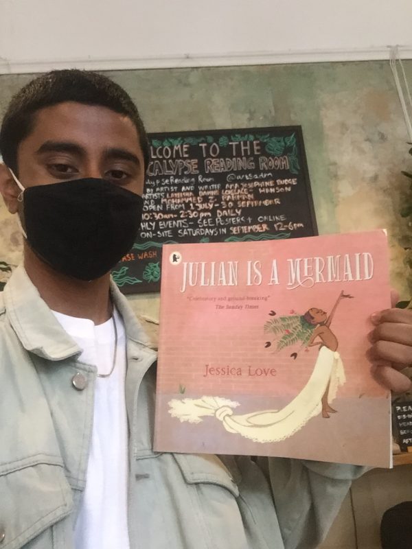 Mohammed holds up the book Julian is a Mermaid