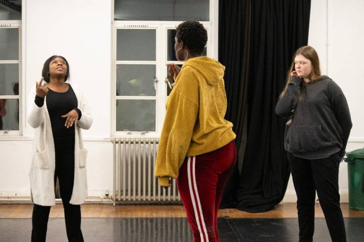 Anna-Maria Nabirye a black woman, stood with two Artsadmin youth members directing a vocal exercise