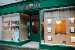 a green store front with 'Art Bomb' signage written in red