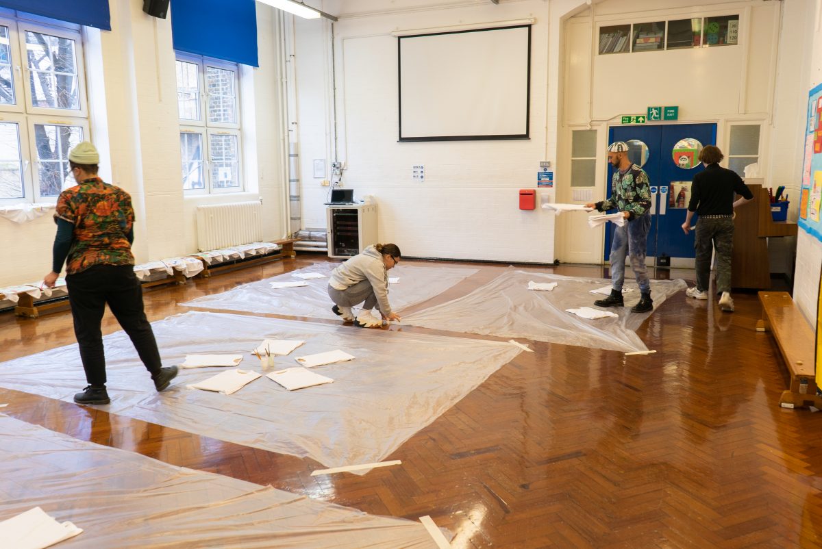 People putting protective film on the floor of a room in a school
