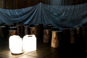 Wooden logs huddled around illuminated water canisters.