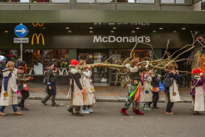 people walking on a street holding a tree in front of McDonald's