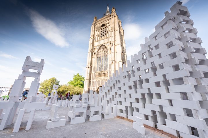 Large tower of dominoes in front of a cathedral