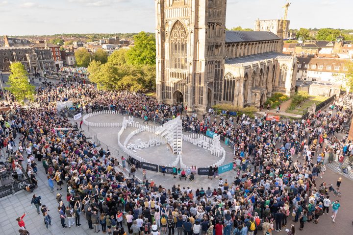 Giant dominoes snake going through a town centre with a large audience