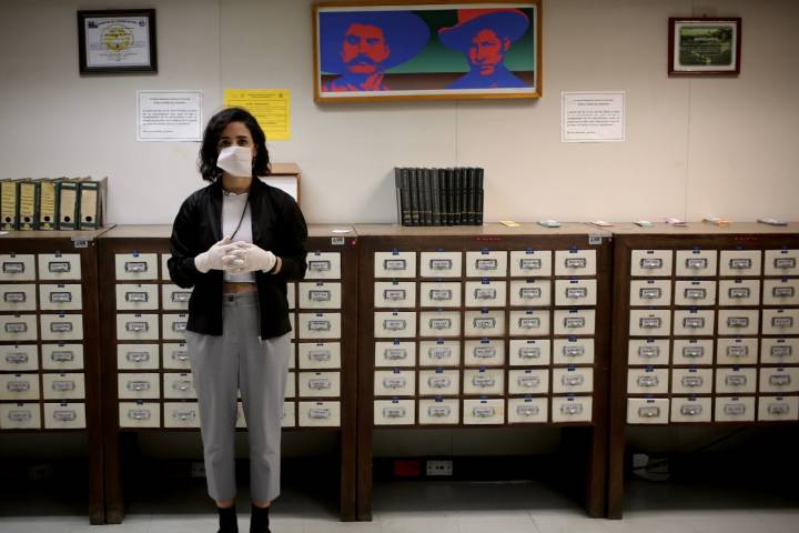 Person wearing mask and gloves stands in archive-like room