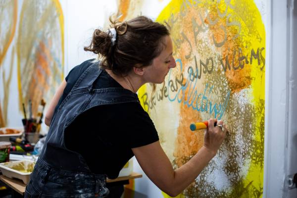 A photo of someone painting a bright yellow mural on the wall